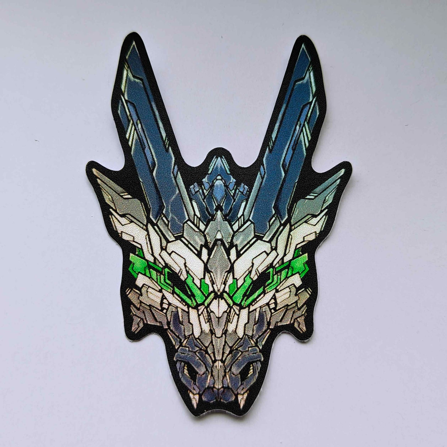 A special holographic sticker in XeneDragon's Generation Three DRGN design, the dragon head colors reflect the same colors as the agender pride flag