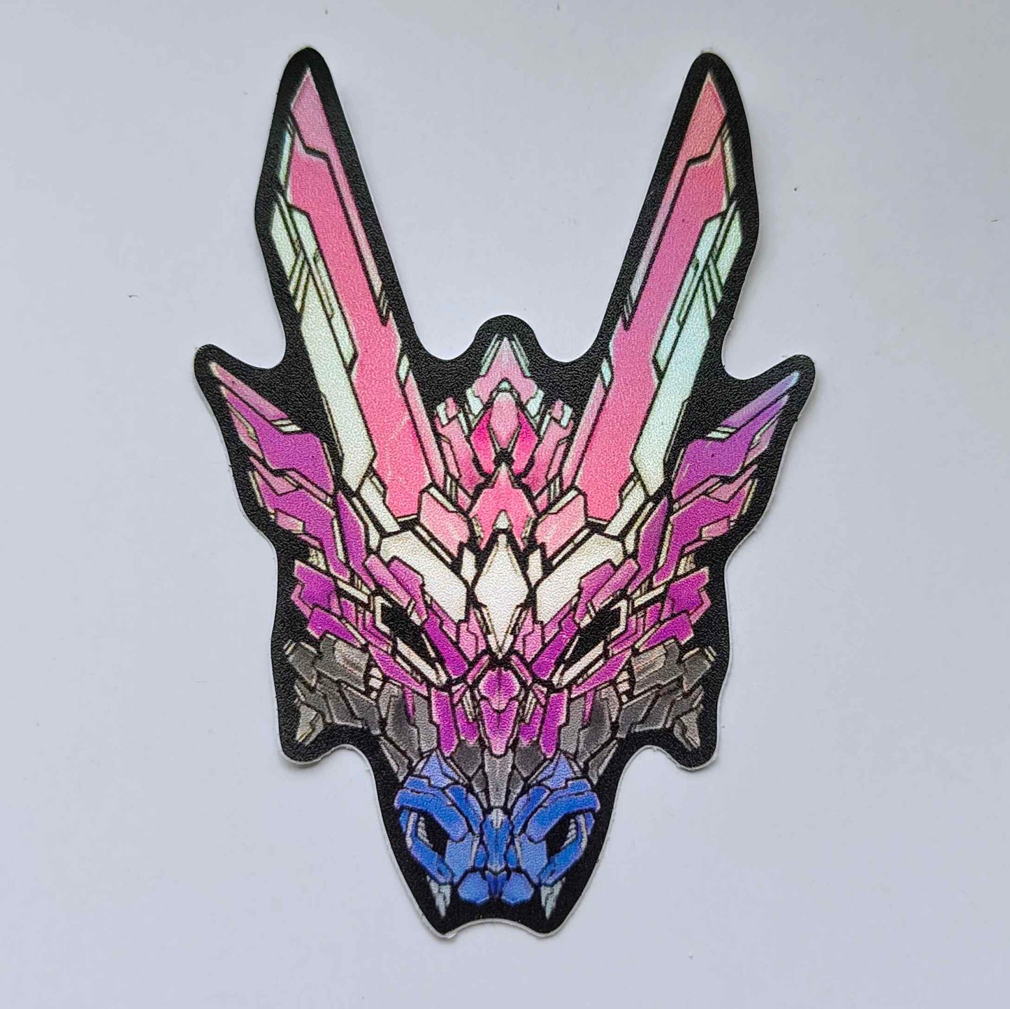 A special holographic sticker in XeneDragon's Generation Three DRGN design, the dragon head colors reflect the same colors as the genderfluid pride flag