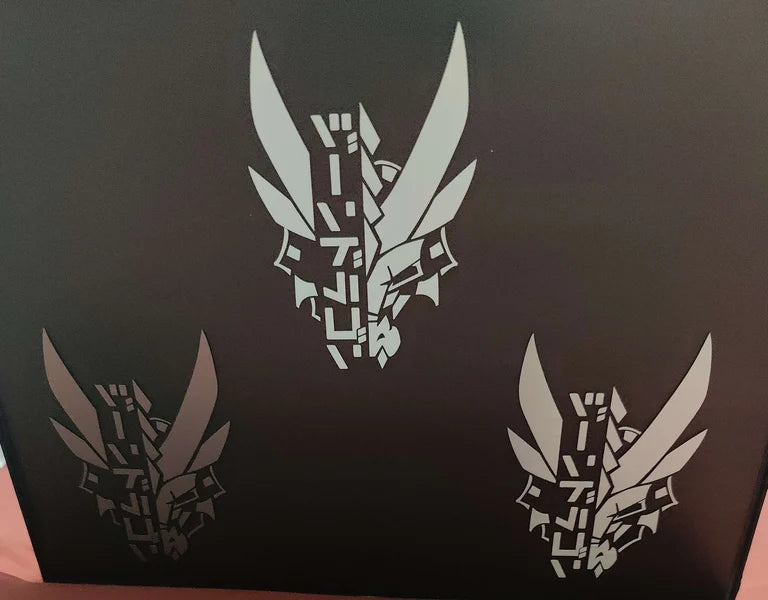 Three dragon decals in a picture frame featuring XeneDragon's Generation 1.1 DRGN design. Picture is taken in low lighting to show the reflective differences between the materials.