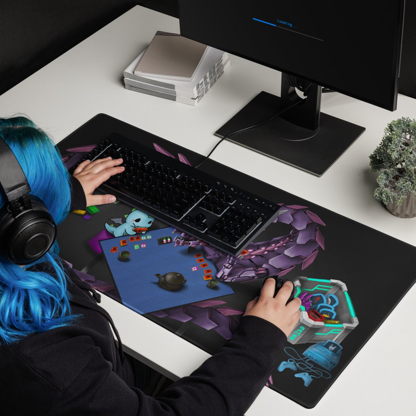 A person with blue hair sits at a desk, using a computer with a large mousepad featuring an illustration of a mechanical dragon playing a trading card game with Neon.
