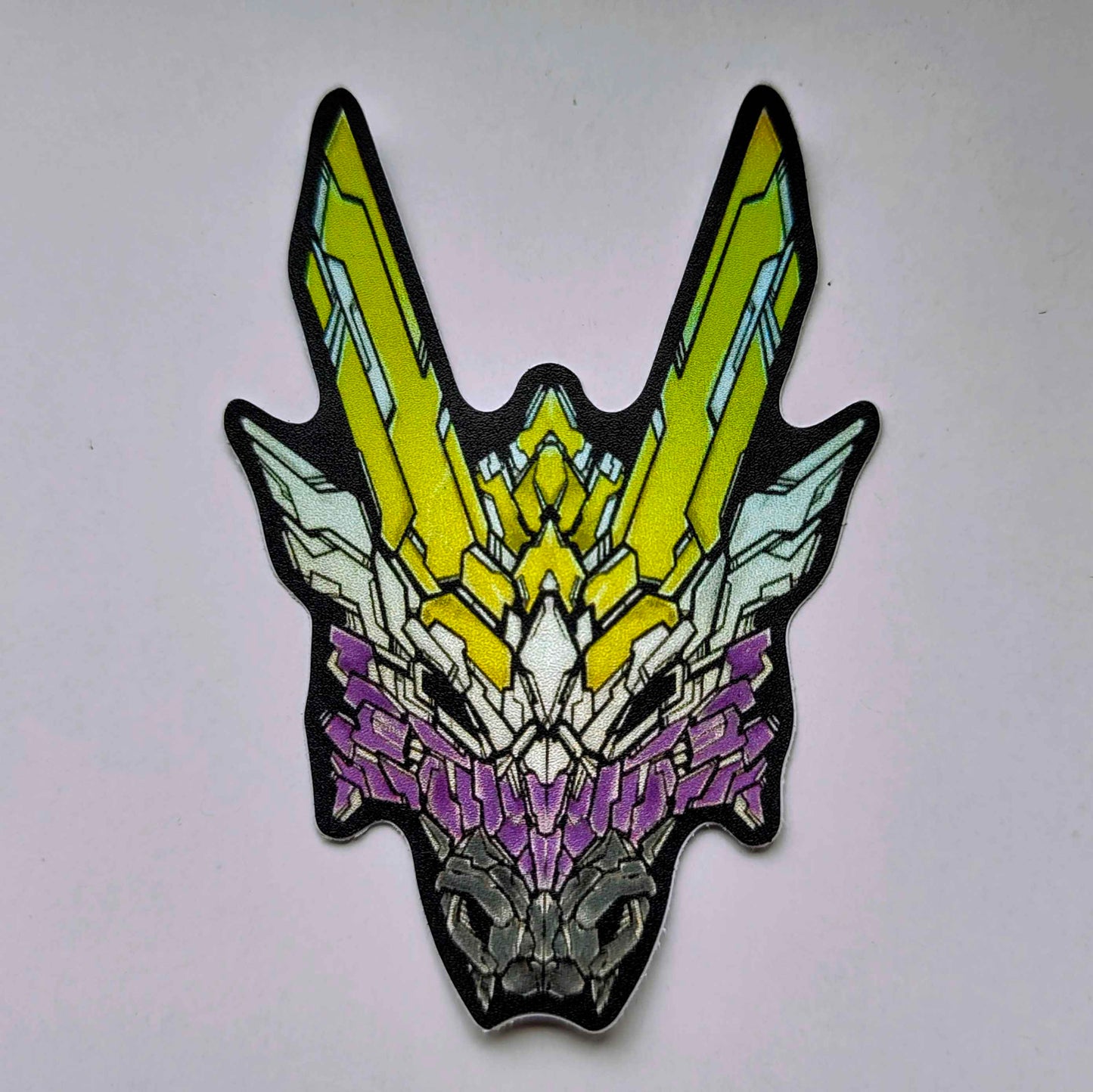 A special holographic sticker in XeneDragon's Generation Three DRGN design, the dragon head colors reflect the same colors as the nonbinary pride flag