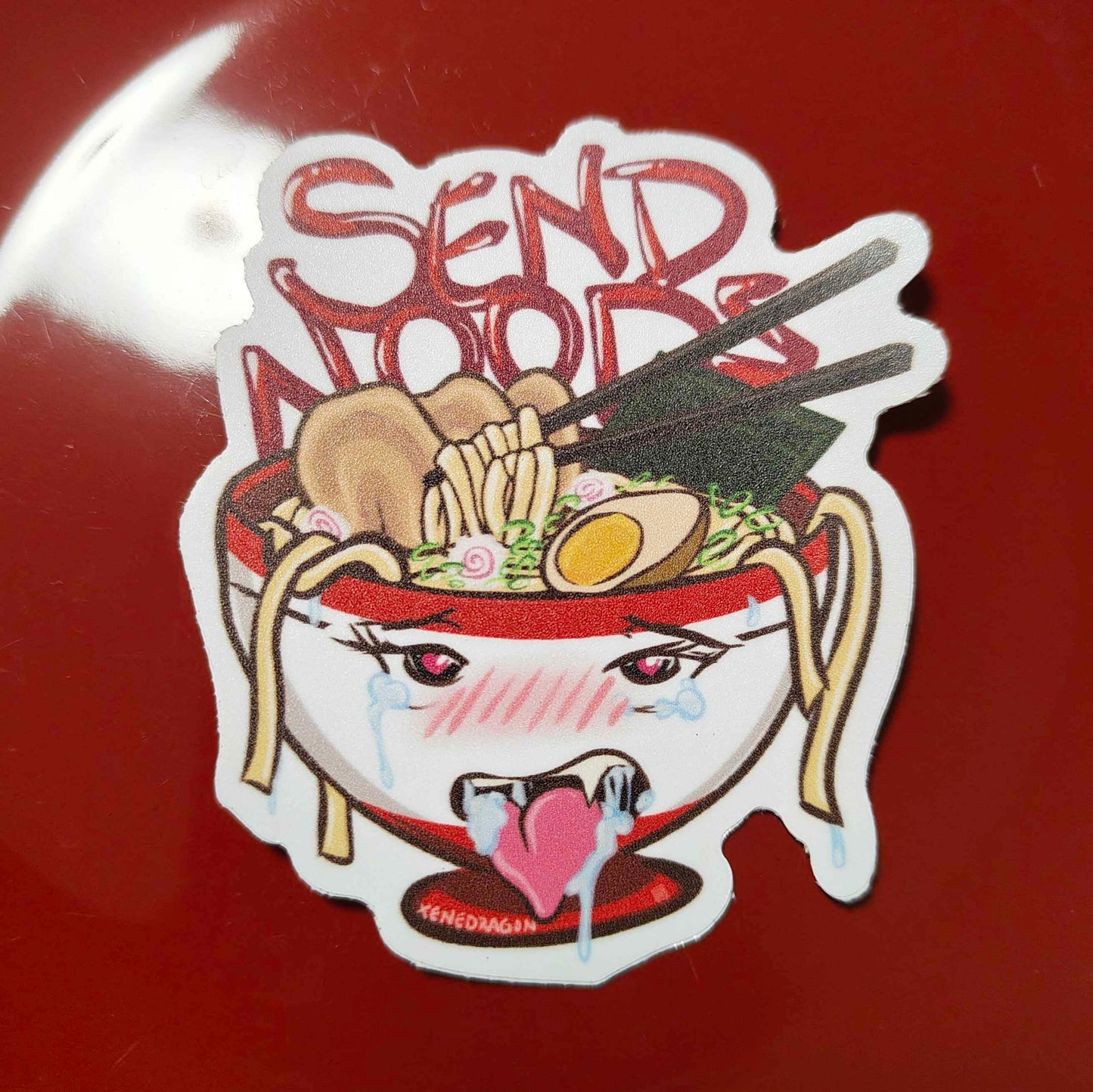 A sticker with the design features a bowl of noodles with a face and the text "Send Noods" written in red.