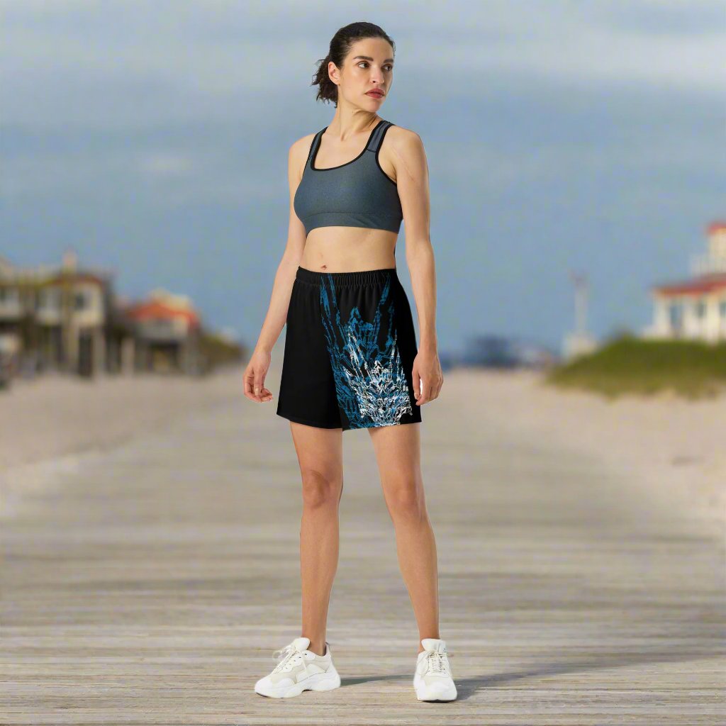 A female model wearing a pair of black athletic shorts with blue and white geometric pattern design based on XeneDragon's generation three DRGN.