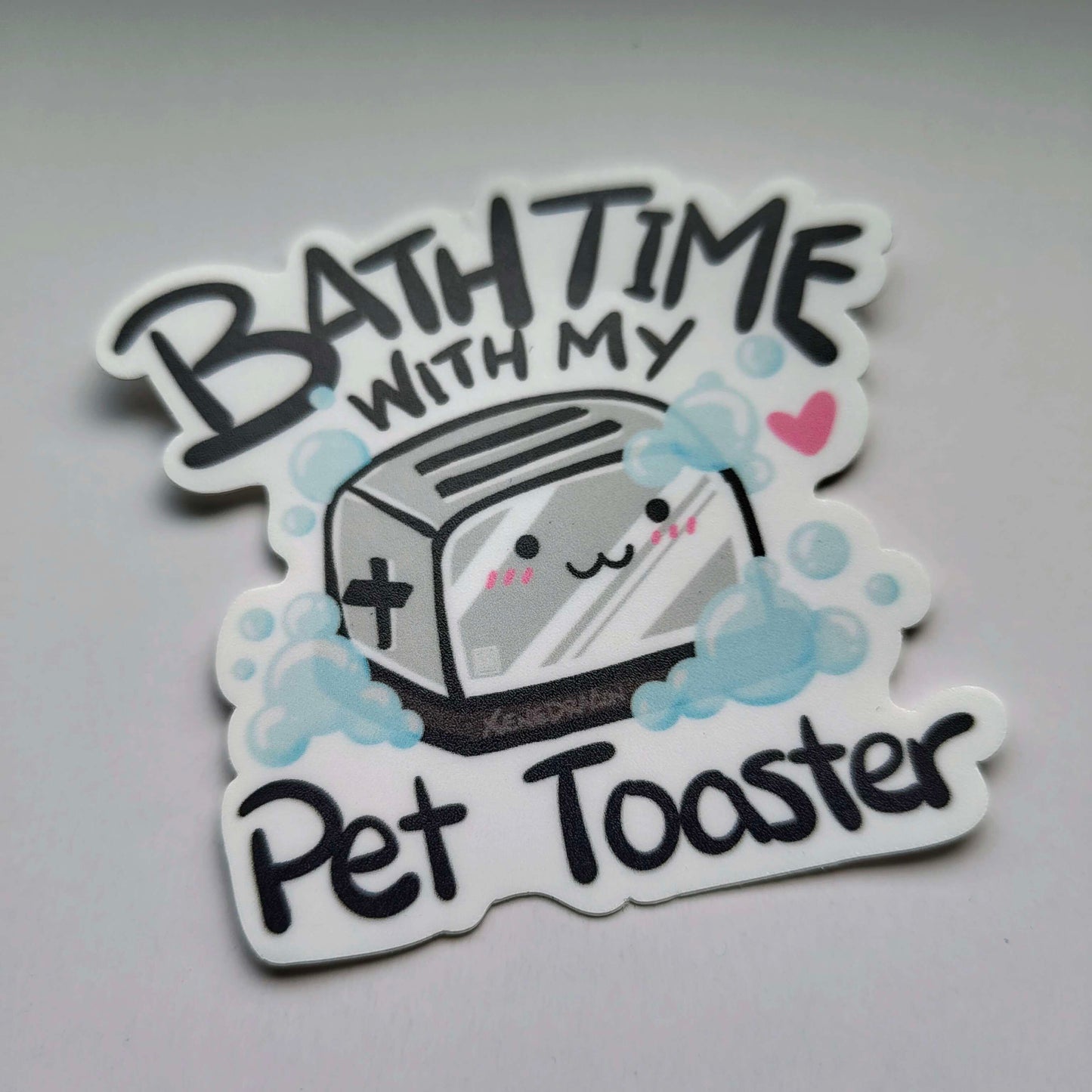 A sticker with the text "Bath Time with My Pet Toaster" and a cartoon illustration of a cute toaster taking a bath.