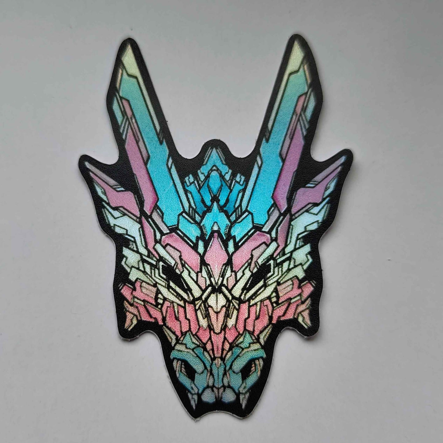 A special holographic sticker in XeneDragon's Generation Three DRGN design, the dragon head colors reflect the same colors as the trans pride flag