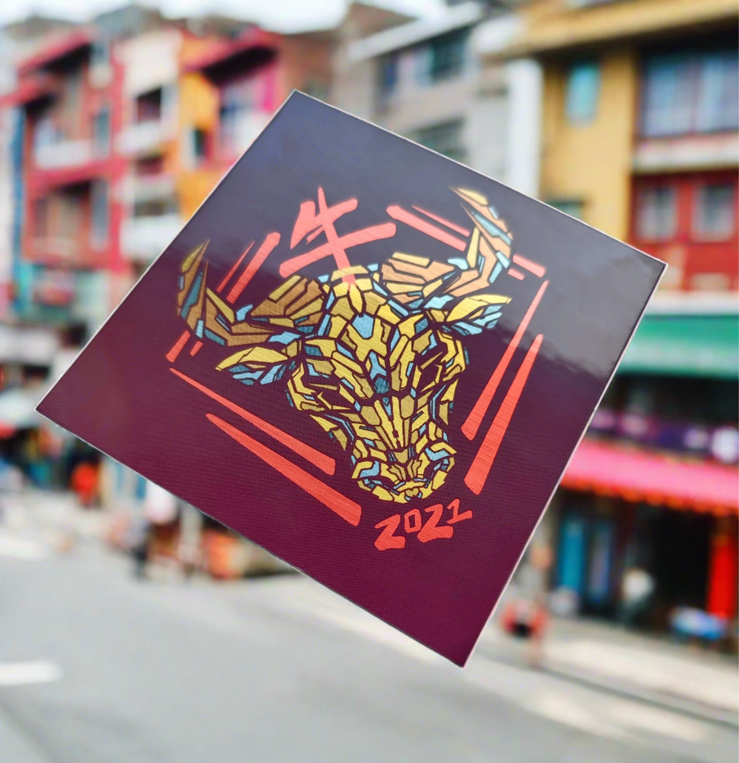 A special metallic effect sticker with a vibrant geometric design celebrating the Year of the Ox. The sticker features a stylized image of an ox's head in gold, with the Chinese character for "ox" and the year "2021" printed below in red. Designed by XeneDragon