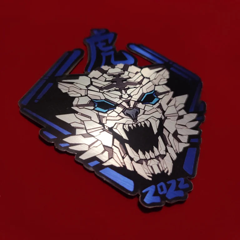 A special metallic effect sticker with a vibrant geometric design celebrating the Year of the Tiger. The sticker features a stylized image of a tiger's head in silver with the Chinese character for "tiger" and the year "2022" printed below in blue. Designed by XeneDragon