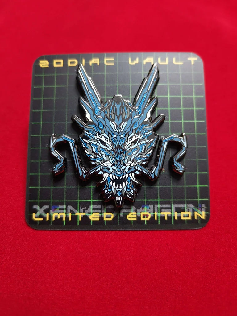 A limited edition enamel pin with vibrant geometric design celebrating the Year of the Dragon. The pin features a stylized image of a dragon's head in blue and white color scheme with special glitter accents. The backing paper for the pin says "ZODIAC VAULT LIMITED EDITION"