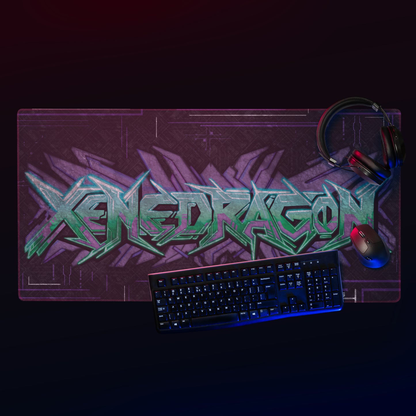 A gaming setup with a keyboard, mouse, and headphones on a large mousepad featuring the "XENEDRAGON" in a vibrant, neon-colored graffiti style design.