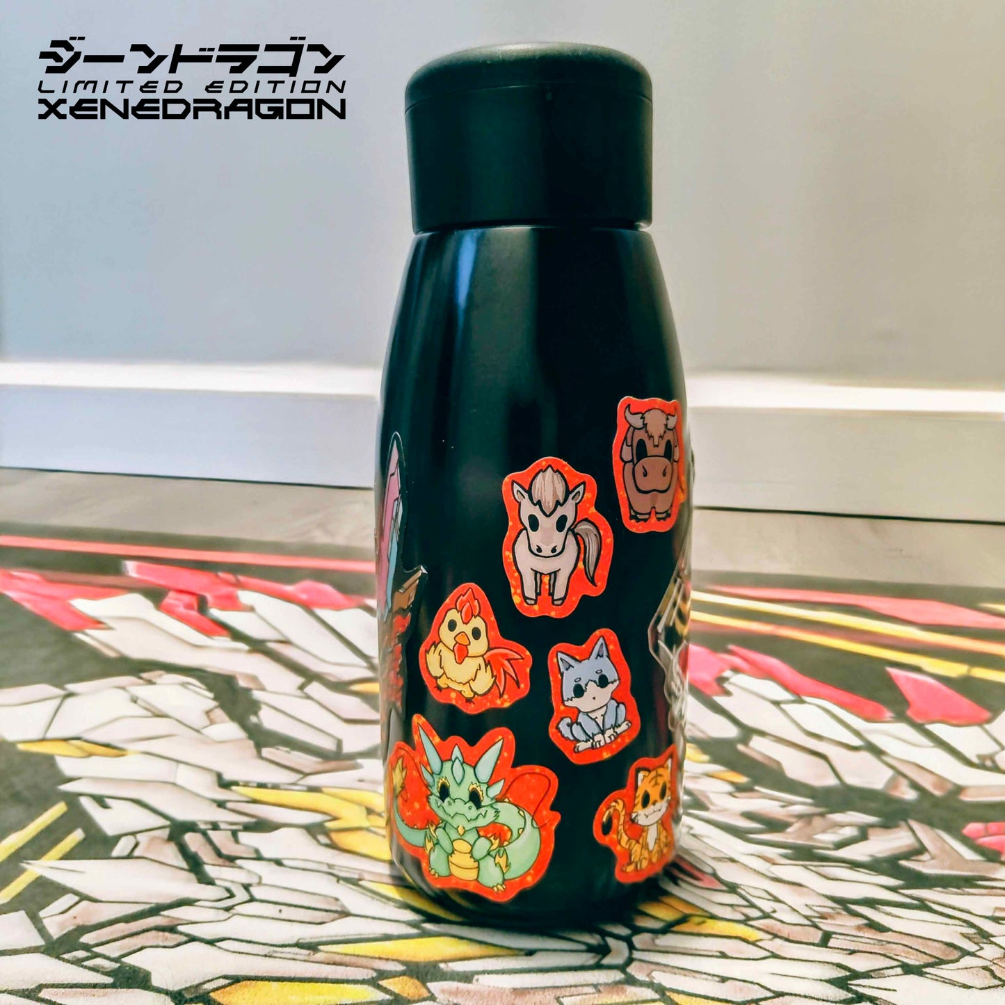 A water bottle displaying stickers of Xenon the Dragon and his Zodiac Friends. These stickers have a red border with gold glitter effects.