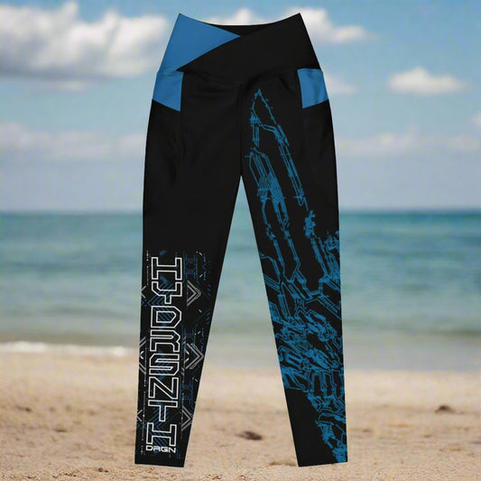 A pair of black leggings with blue accents and a blue and white geometric pattern design based on XeneDragon's generation three DRGN. The leggings have pockets and the word "HYDRSYNTH" is written on one leg.