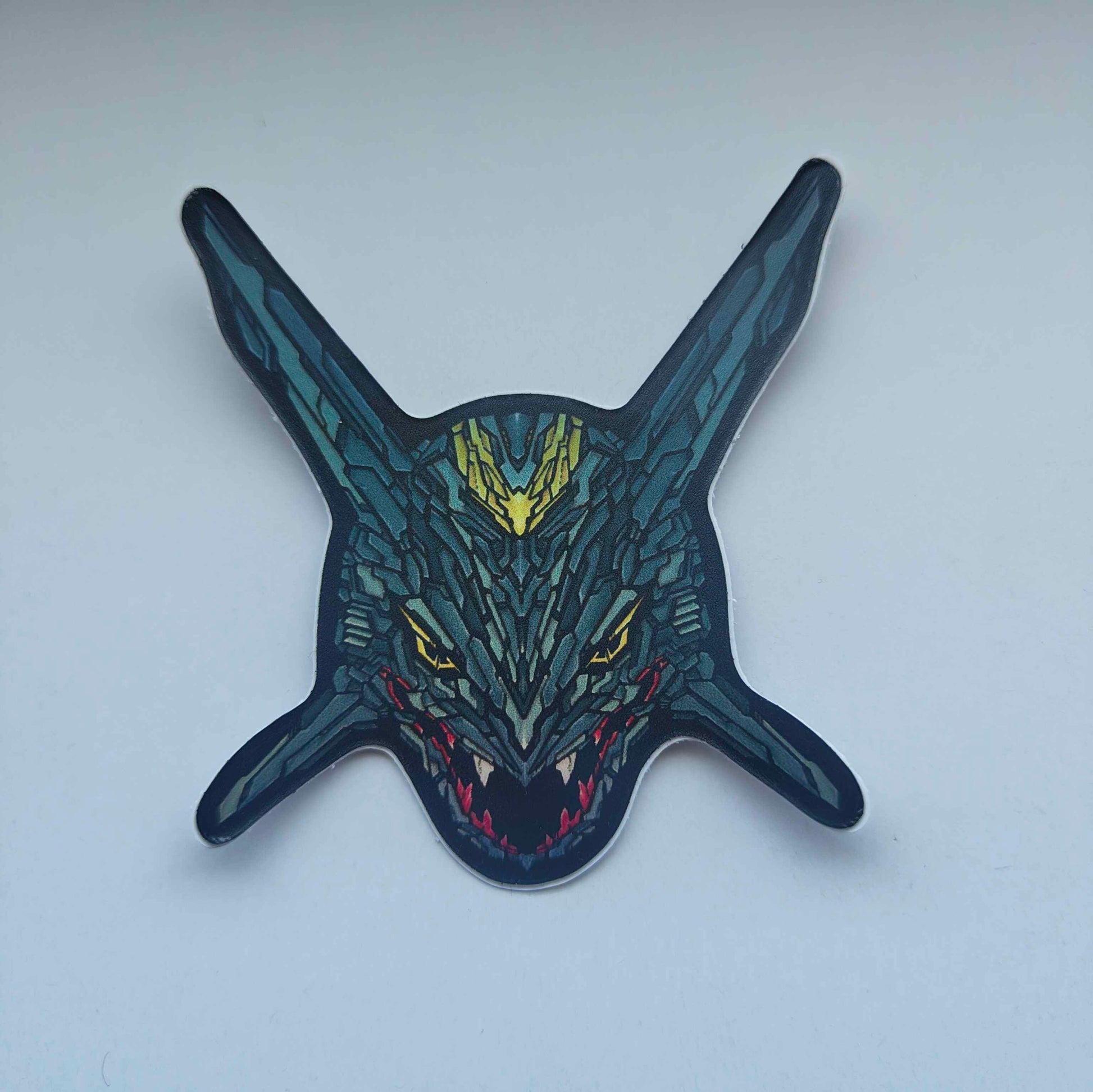 A special iridescent effect sticker with a detailed design of a stylized dragon's head. The design features a dark color scheme with yellow and red accents. Designed by XeneDragon.