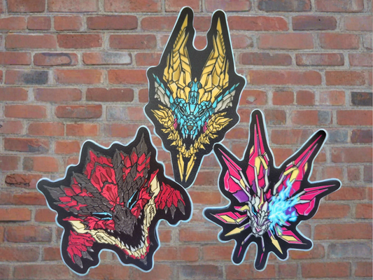 Three vibrant stickers depicting stylized monster heads are affixed to a brick wall. Each sticker showcases a unique design with distinct colors and mecha textures made by XeneDragon